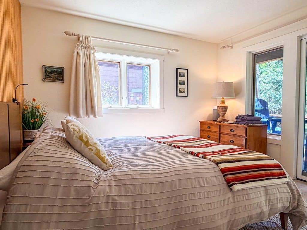 Queen bedroom with forest-view window at Boom Chalet